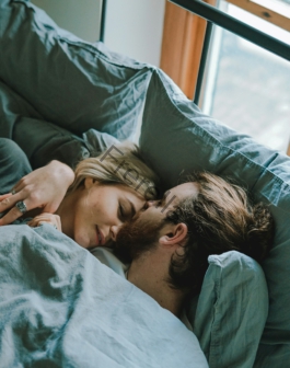 man kissing woman's forehead while lying on bed