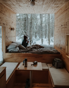 woman sitting on bed watching by the window during winter