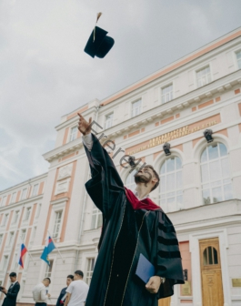 a person in a robe holding a gun in front of a building