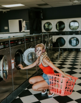 woman kneeling in front of front-load clothes washer inside laundry shop