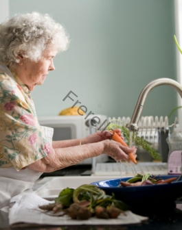 woman wearing yellow and pink floral dress wahing carrots