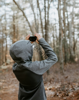 man in gray sweater holding black camera