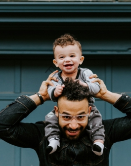 man in black leather jacket carrying boy in black leather jacket
