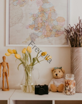 a vase with flowers and a teddy bear on a shelf