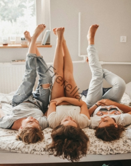 three women lying on bed while raising their feet