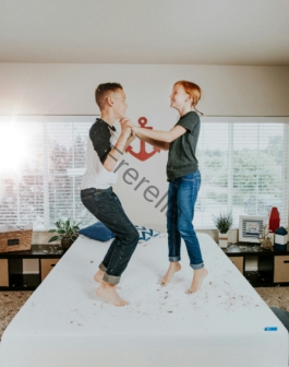 boy and girl jumping on white bed mattress inside room