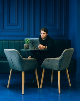 man sitting on couch with looking at his MacBook on table