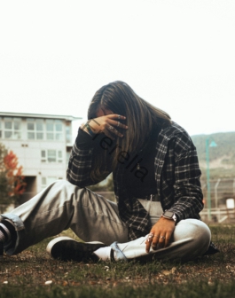 a woman sitting on the ground with her head in her hands