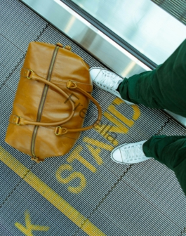 person stranding beside brown leather handbag