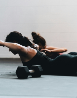 woman in black tank top and black leggings lying on black floor