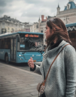 a woman standing in front of a blue bus