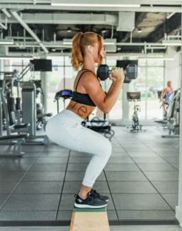 woman wearing black sports bra and white legging lifting dummbells